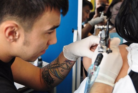 Мастер делает татуировку